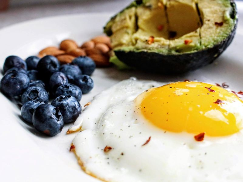 a nutritious breakfast featuring a fried egg, avocado, blueberries, an image