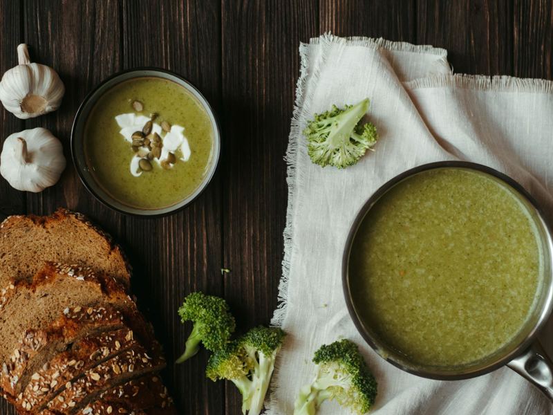 delicious creamy broccoli soup with bread and garlic on a wooden table image