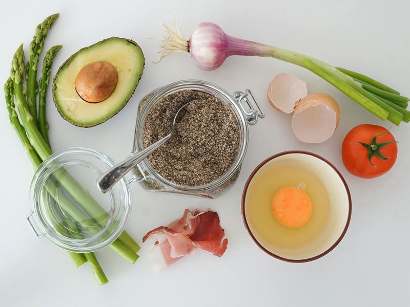 flat lay of fresh asparagus, avocado, egg, tomato, and more for a keto image